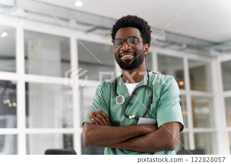 Happy African American male doctor wearing uniform and stethoscope looking at camera Happy African American male doctor wearing uniform and stethoscope looking at camera 122828057