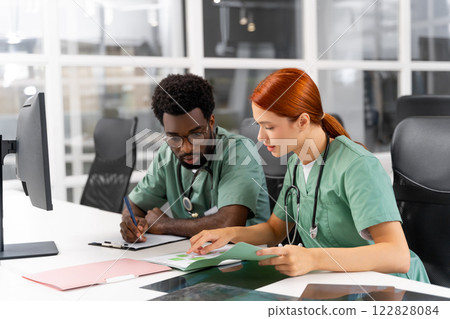 Diverse doctors collaborating on surgery discussing diagnosis and reading X-ray 122828084