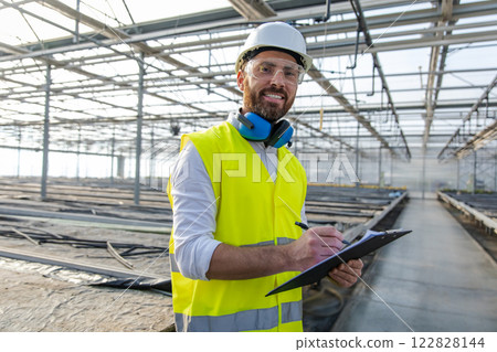 Male engineer in hardhat and protective glasses inspecting construction site 122828144