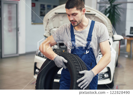 Mechanic holding a tire tire at the repair garage. replacement of winter and summer tires 122828490