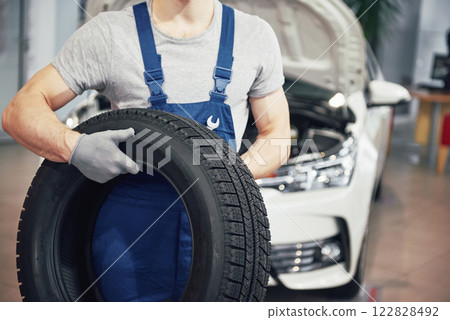 Mechanic holding a tire tire at the repair garage. replacement of winter and summer tires Mechanic holding a tire tire at the repair garage. replacement of winter and summer tires 122828492