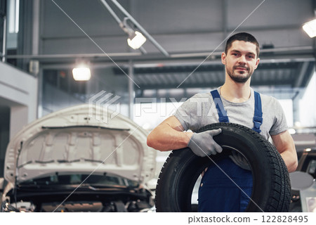 Mechanic holding a tire tire at the repair garage. replacement of winter and summer tires Mechanic holding a tire tire at the repair garage. replacement of winter and summer tires 122828495