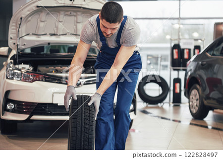 Mechanic holding a tire tire at the repair garage. replacement of winter and summer tires 122828497