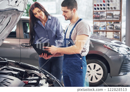 A man mechanic and woman customer discussing repairs done to her vehicle 122828513