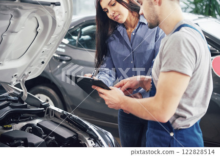 A man mechanic and woman customer discussing repairs done to her vehicle 122828514