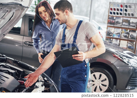 A man mechanic and woman customer discussing repairs done to her vehicle 122828515