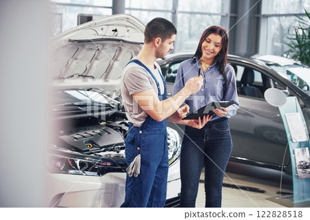A man mechanic and woman customer discussing repairs done to her vehicle 122828518