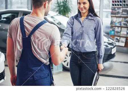 husband car mechanic and woman customer make an agreement on the repair of the car 122828526