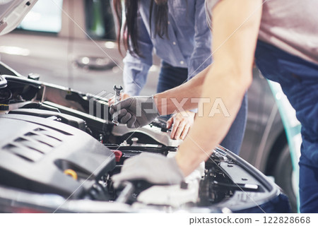 A man mechanic and woman customer look at the car hood and discuss repairs 122828668
