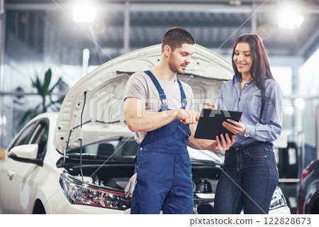 A man mechanic and woman customer discussing repairs done to her vehicle 122828673