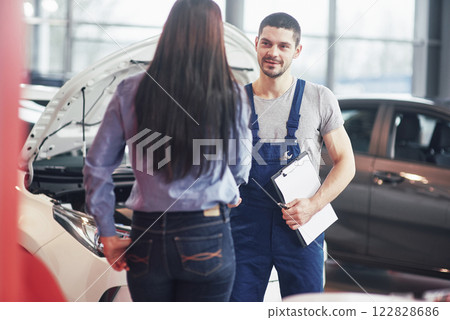 husband car mechanic and woman customer make an agreement on the repair of the car 122828686