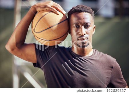 Portrait african american man standing with a basketball on the court. Fitness male athlete or player holding a sports ball after playing, training and practice game in the background on a court 122829837