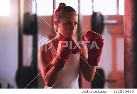 Boxing, training and woman or boxer in gym exercising for fitness, motivation and workout. Sport, wellness and health with girl fighter or athlete in sports club ready to train for exercise or fight. 122830439