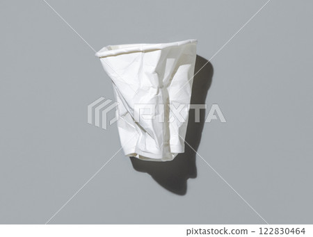 Used and crumpled disposable white paper cup on a gray top view, hard shadow. Consumerism concept Used and crumpled disposable white paper cup on a gray top view, hard shadow. Consumerism concept 122830464