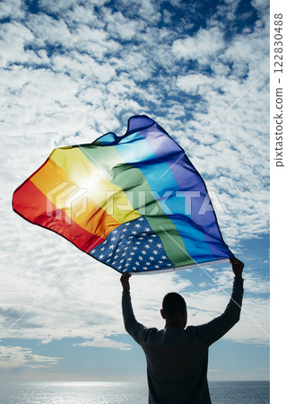 man waving a rainbow american flag on the sky 122830488