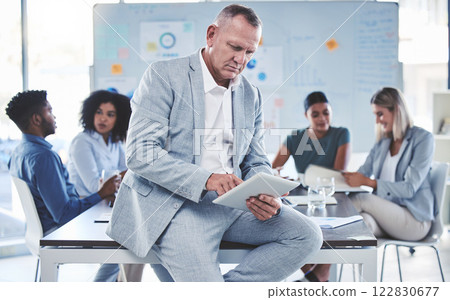 Businessman, leader or ceo with a tablet against the boardroom table after a meeting. Team or colleagues in the background planning and brainstorming for a startup project in an office boardroom 122830677