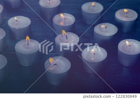 Tea light candles on a dark background, many lights in the dark Tea light candles on a dark background, many lights in the dark 122830849