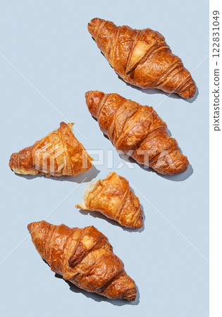 Fresh croissants on blue background with shadow. Creative layout for cafe advertising  122831049