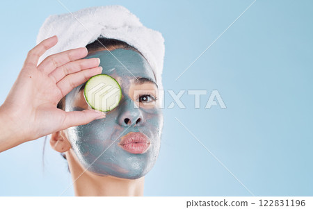 Beauty, cosmetics and skincare by woman grooming with a face treatment and cucumber against studio background. Young female enjoy self care and organic products during routine pamper wellness session Beauty, cosmetics and skincare by woman grooming with a face treatment and cucumber against studio background. Young female enjoy self care and organic products during routine pamper wellness session 122831196