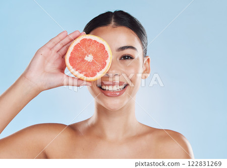 Fruit, beauty and skin of a woman with smile holding a grapefruit on her face against a blue studio background. Portrait of a happy female model in healthy, juicy and natural skincare for healthcare. 122831269