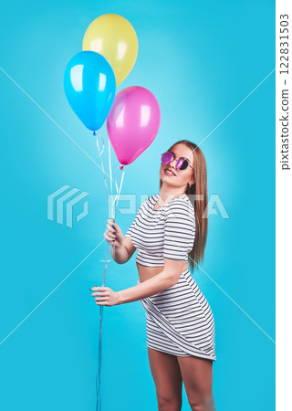 Happy smiling woman is looking on an air colorful balloons having fun over a blue background 122831503