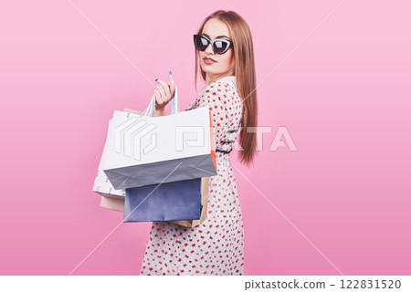 Portrait of young happy smiling woman with shopping bags on the pink Background Portrait of young happy smiling woman with shopping bags on the pink Background 122831520