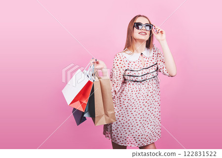 Portrait of young happy smiling woman with shopping bags on the pink Background 122831522