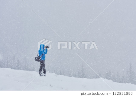 Man with backpack goes across coniferous forest after snow storm. Back view, toned image Man with backpack goes across coniferous forest after snow storm. Back view, toned image 122831893