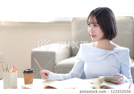 A young woman studying alone in the living room 122832036