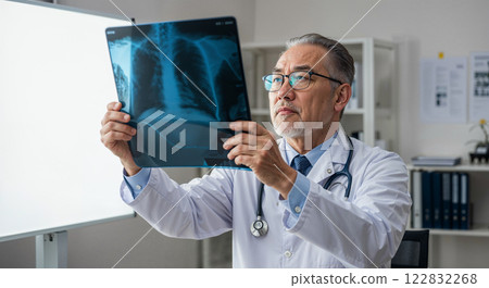 Experienced doctor examining x-ray in clinic during daylight, focused on patient diagnosis and health assessment 122832268