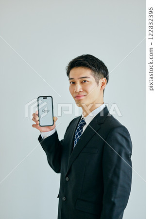 A young man in his twenties holding a smartphone 122832396