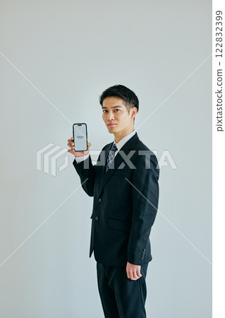 A young man in his twenties holding a smartphone 122832399