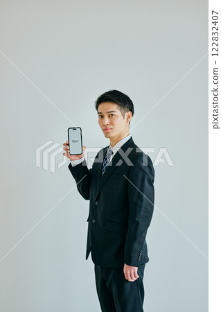 A young man in his twenties holding a smartphone 122832407