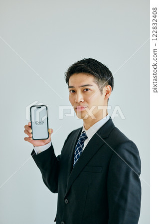 A young man in his twenties holding a smartphone 122832408