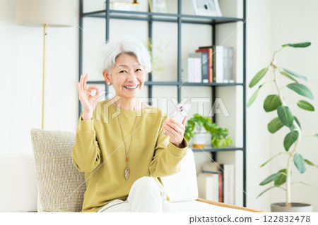Senior woman using a smartphone in the living room 122832478