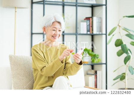 Senior woman using a smartphone in the living room Senior woman using a smartphone in the living room 122832480