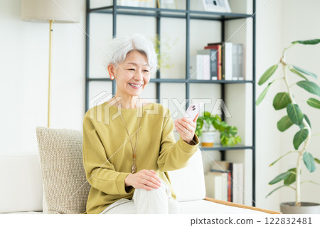 Senior woman using a smartphone in the living room Senior woman using a smartphone in the living room 122832481