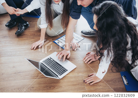 Young creative people in modern office. Group of young business people are working together with laptop. Freelancers sitting on the floor. Cooperation corporate achievement. Teamwork concept 122832609