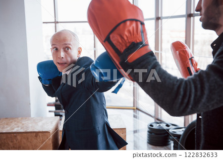 An angry bald businessman beats a boxing pear in the gym. concept of anger management 122832633