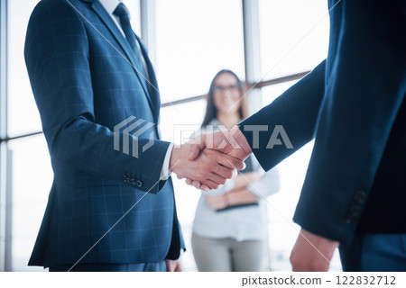 Two confident business man shaking hands during a meeting in the office, success, dealing, greeting and partner concept 122832712