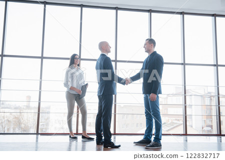 Two confident business man shaking hands during a meeting in the office, success, dealing, greeting and partner concept 122832717