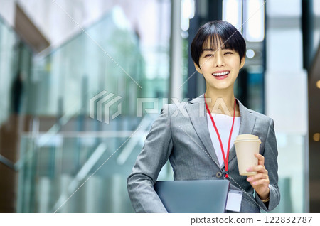 一位身穿西裝的女商人拿著筆記型電腦在辦公室工作。 122832787