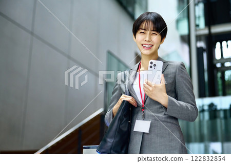 一位身穿西裝、手拿筆記型電腦的女商人正在上班。 一位身穿西裝、手拿筆記型電腦的女商人正在上班。 122832854