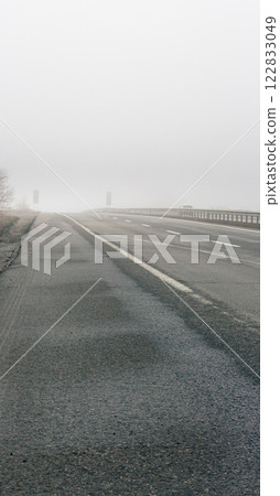 Empty highway in the fog. Bad weather on the road. Road on foggy day in perspective with copy space. Driving conditions concept. Ghostly misty road. Caution and danger on the road. Moody weather Empty highway in the fog. Bad weather on the road. Road on foggy day in perspective with copy space. Driving conditions concept. Ghostly misty road. Caution and danger on the road. Moody weather 122833049