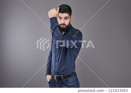 Handsome young bearded man is looking away while standing against gray background Handsome young bearded man is looking away while standing against gray background 122833083