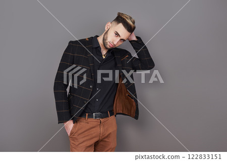 Successful young businessman in a brown suit with a lovely genuine smile posing against a dark grey background with copy space 122833151