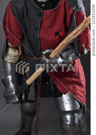 Medieval knight on grey background. Portrait of brutal dirty face warrior with chain mail armour red and black clothes and battle axe 122833206