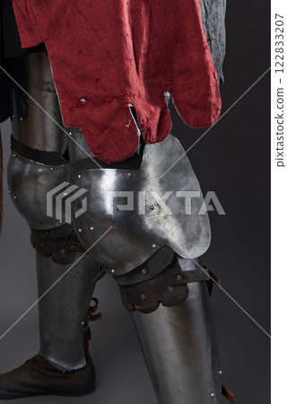 Medieval knight on grey background. Portrait of brutal dirty face warrior with chain mail armour red and black clothes and battle axe 122833207