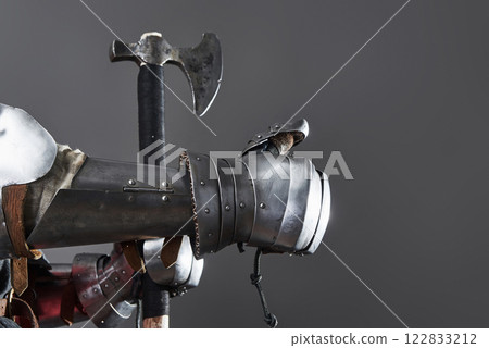 Medieval knight on grey background. Portrait of brutal dirty face warrior with chain mail armour red and black clothes and battle axe 122833212