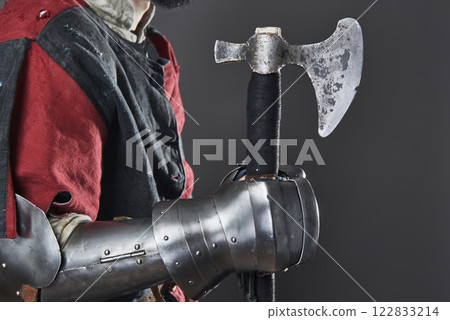 Medieval knight on grey background. Portrait of brutal dirty face warrior with chain mail armour red and black clothes and battle axe Medieval knight on grey background. Portrait of brutal dirty face warrior with chain mail armour red and black clothes and battle axe 122833214